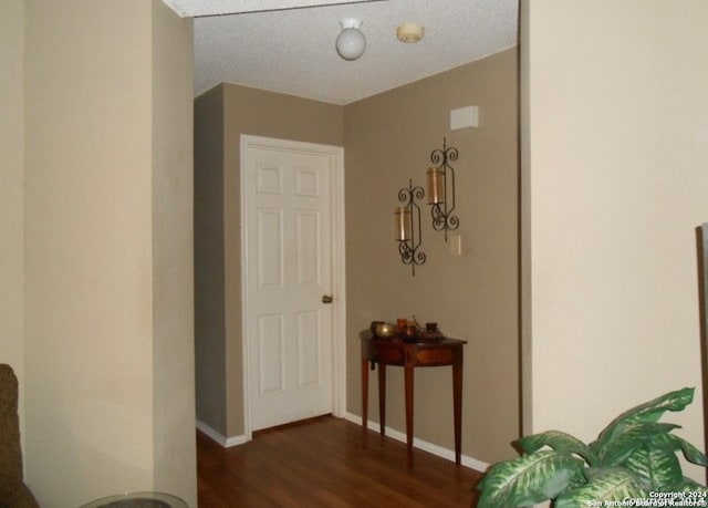 hall with dark wood-type flooring and a textured ceiling