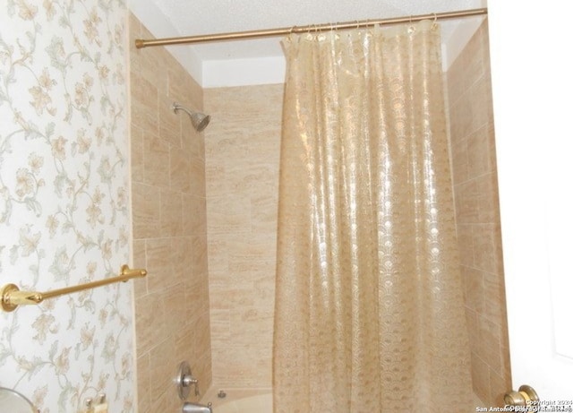 bathroom with shower / bathtub combination with curtain and a textured ceiling