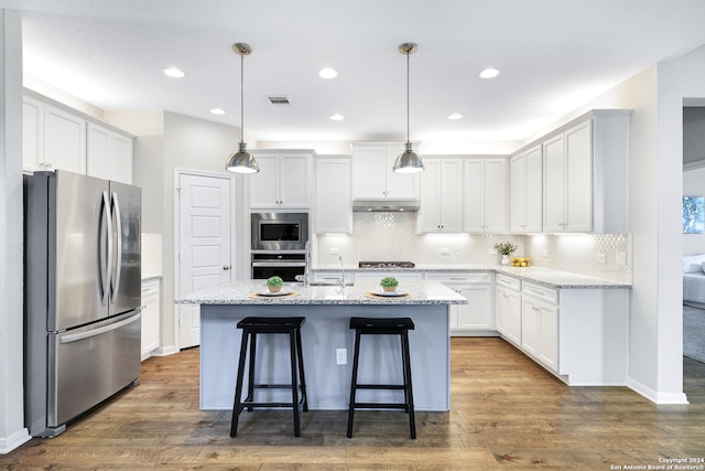 kitchen featuring a kitchen island with sink, hanging light fixtures, dark hardwood / wood-style floors, and appliances with stainless steel finishes