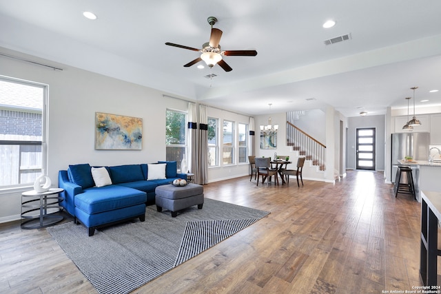 living room featuring hardwood / wood-style floors and ceiling fan with notable chandelier