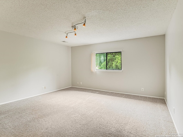 carpeted spare room featuring a textured ceiling and rail lighting