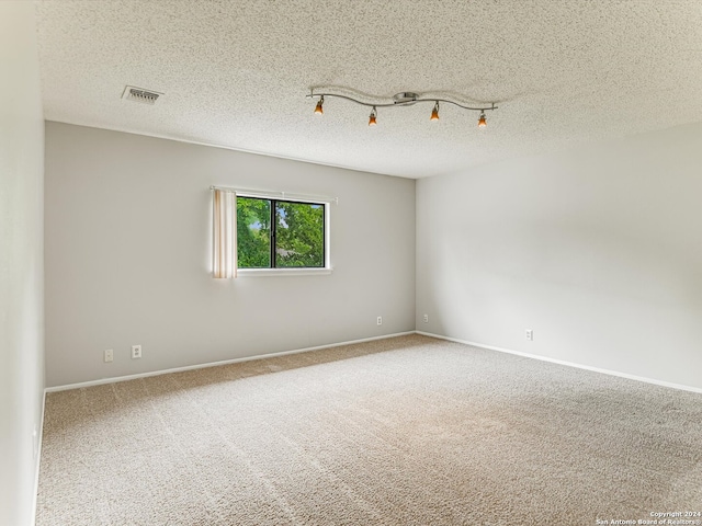 spare room with rail lighting, carpet floors, and a textured ceiling