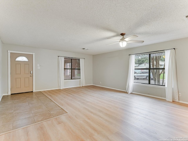 entryway with a textured ceiling, light hardwood / wood-style flooring, and ceiling fan