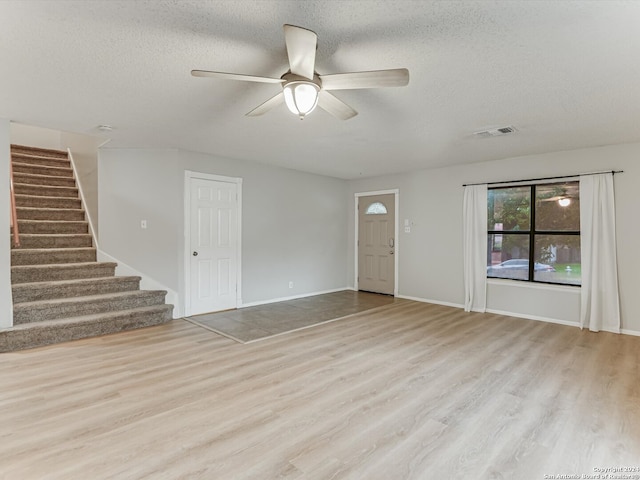 unfurnished living room featuring a textured ceiling, ceiling fan, and light wood-type flooring