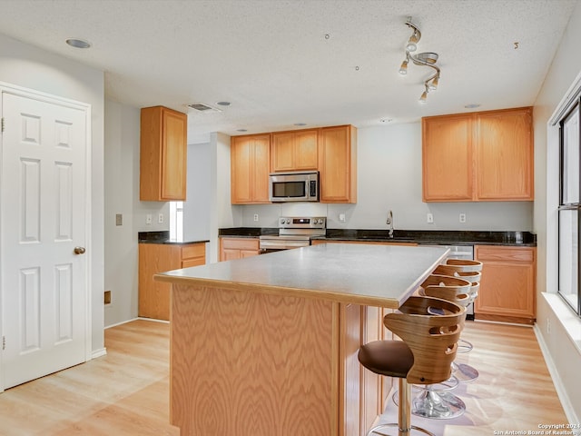 kitchen featuring light hardwood / wood-style flooring, a kitchen island, stainless steel appliances, and sink