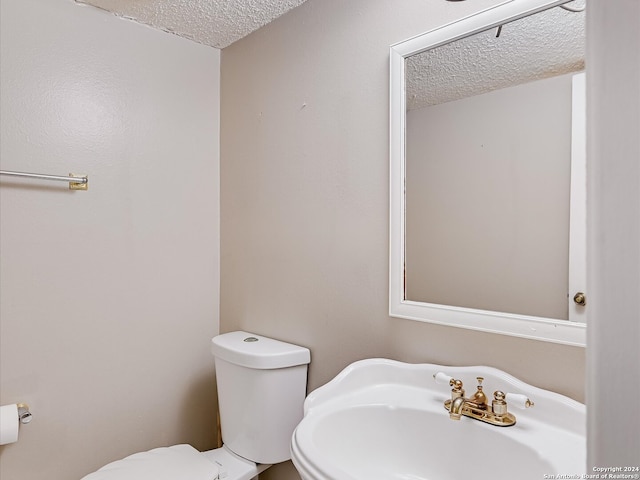 bathroom featuring toilet, sink, and a textured ceiling