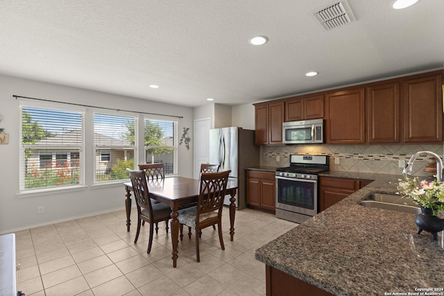 kitchen featuring light tile patterned flooring, a sink, visible vents, appliances with stainless steel finishes, and backsplash