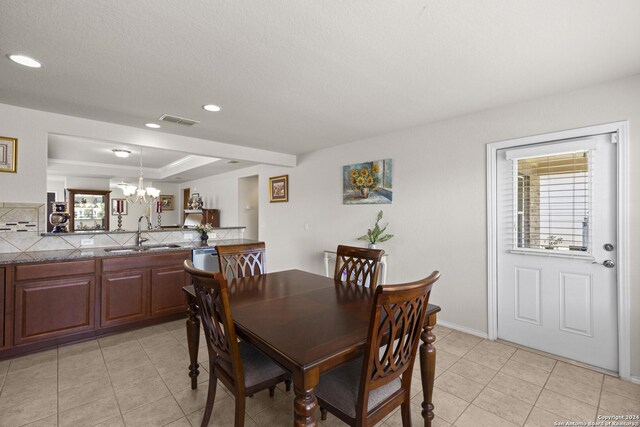 tiled dining area with an inviting chandelier, plenty of natural light, and sink