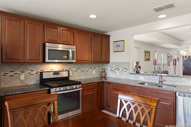 kitchen featuring stainless steel appliances, sink, stone counters, and a notable chandelier