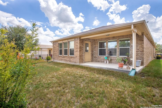 rear view of house featuring brick siding, a lawn, a patio, and fence