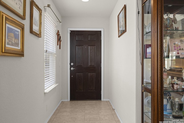 doorway to outside with light tile patterned floors, baseboards, and a healthy amount of sunlight