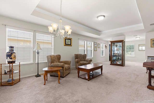 carpeted living room featuring a tray ceiling, ornamental molding, and an inviting chandelier