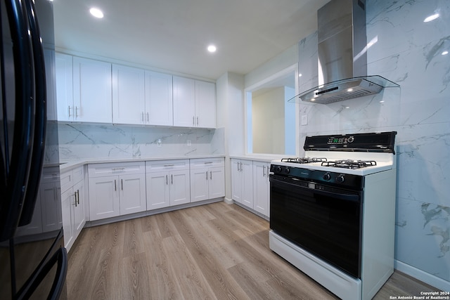 kitchen featuring light wood-type flooring, island range hood, white range with gas stovetop, white cabinets, and black fridge