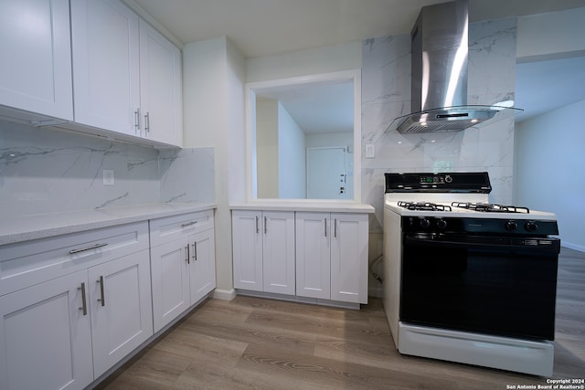 kitchen featuring light hardwood / wood-style flooring, decorative backsplash, white gas stove, island exhaust hood, and white cabinets