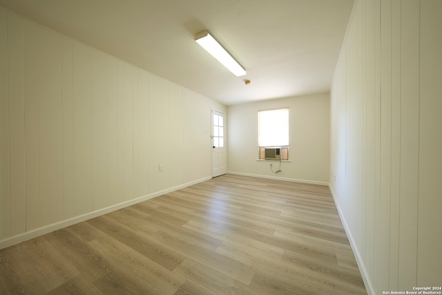 spare room with cooling unit, wood walls, and light wood-type flooring