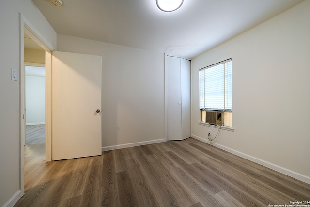 unfurnished bedroom with cooling unit, a closet, and hardwood / wood-style flooring