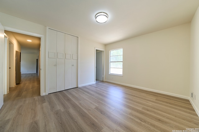 unfurnished bedroom featuring light hardwood / wood-style flooring and a closet