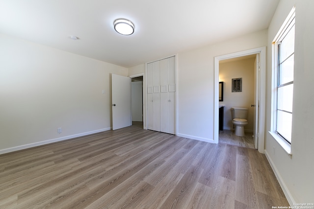 unfurnished bedroom with light hardwood / wood-style flooring, a closet, and ensuite bathroom