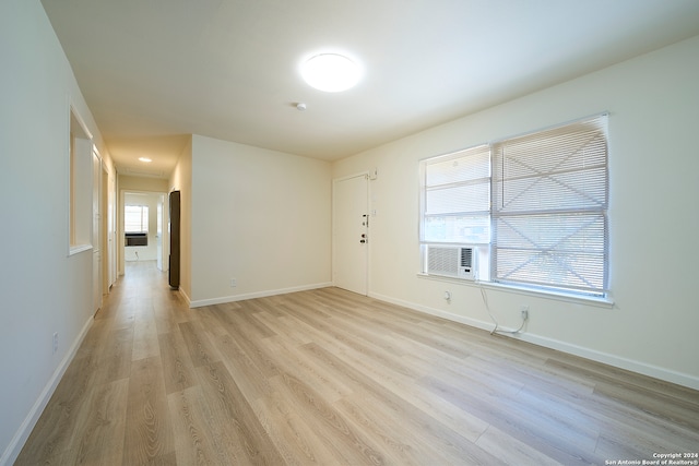 empty room with light wood-type flooring, cooling unit, and plenty of natural light