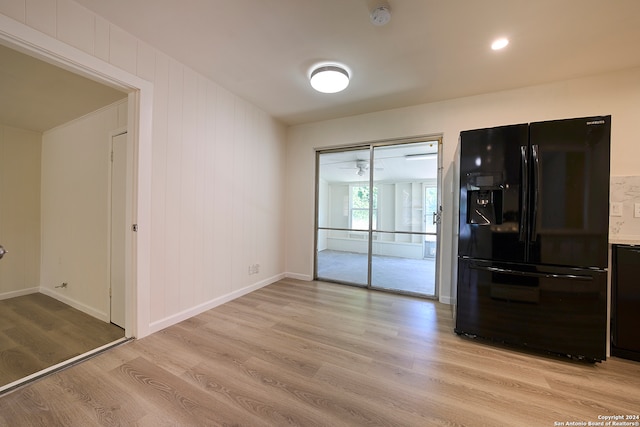 kitchen with light hardwood / wood-style flooring and black fridge with ice dispenser