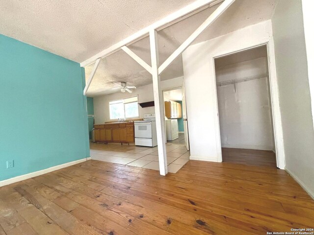 unfurnished living room with a textured ceiling, ceiling fan, light hardwood / wood-style floors, and sink