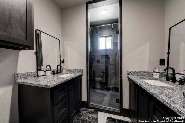 bathroom featuring tile patterned flooring, walk in shower, toilet, and vanity