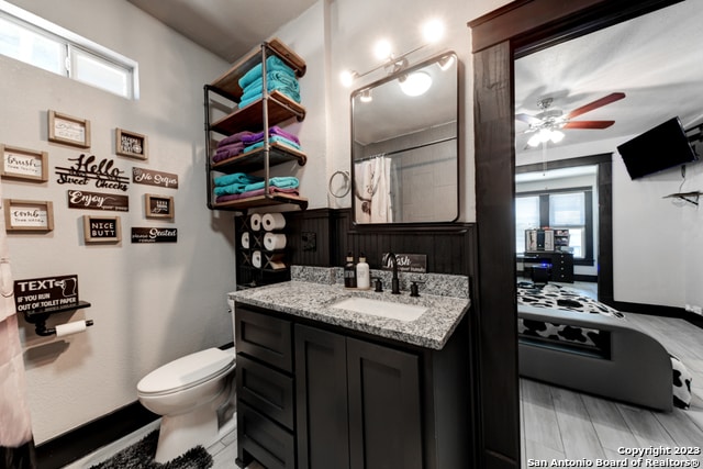 bathroom with ceiling fan, toilet, walk in shower, and vanity