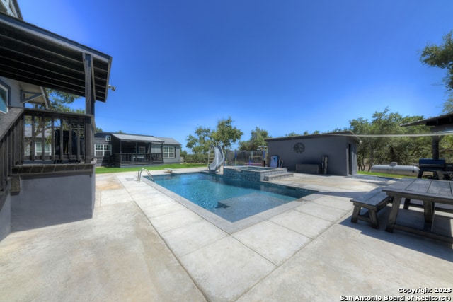 view of pool with a water slide and a patio