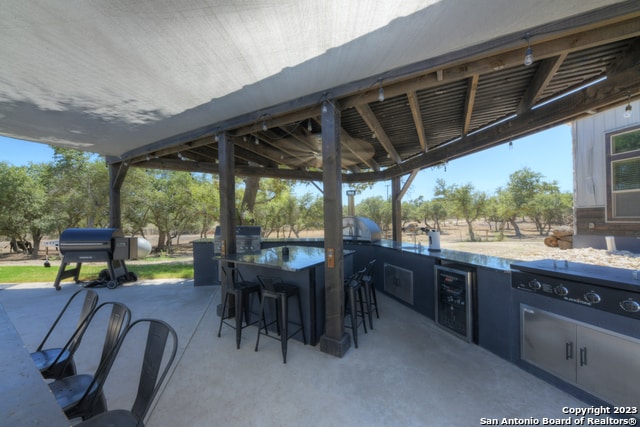 view of patio / terrace with exterior kitchen, a bar, area for grilling, and wine cooler