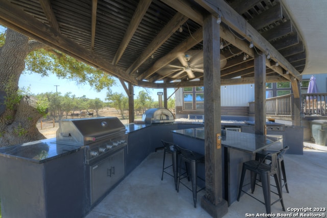 view of patio with exterior kitchen, a bar, and area for grilling