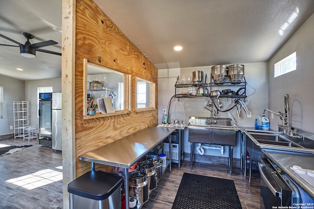 kitchen with dark wood-type flooring, ceiling fan, sink, and stainless steel refrigerator