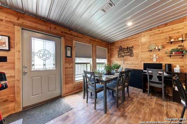 dining area with vaulted ceiling, wood-type flooring, wood walls, and wood ceiling