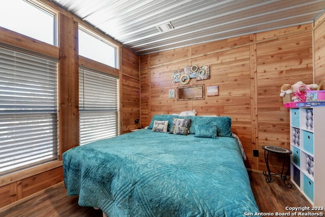 bedroom with wooden walls and dark hardwood / wood-style floors