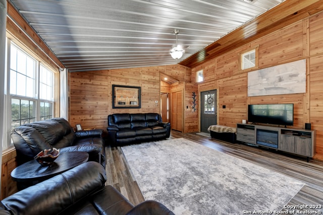 living room with vaulted ceiling, hardwood / wood-style floors, wooden walls, and wooden ceiling