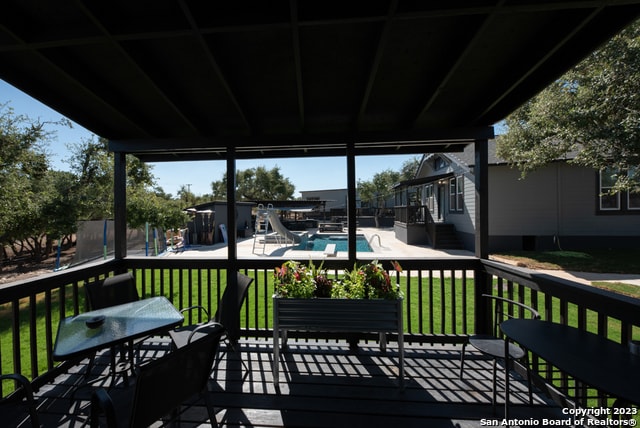 wooden deck with a fenced in pool, a yard, and a patio