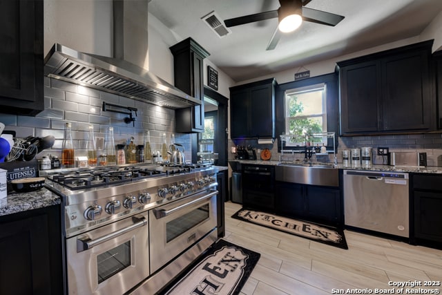 kitchen featuring appliances with stainless steel finishes, decorative backsplash, wall chimney exhaust hood, and ceiling fan