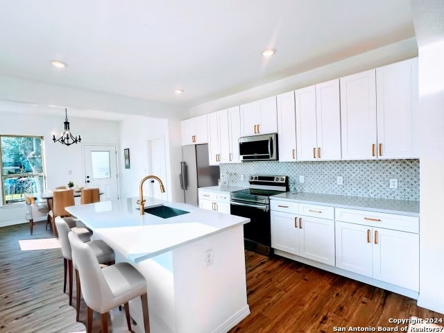 kitchen featuring dark hardwood / wood-style flooring, a center island with sink, stainless steel appliances, sink, and white cabinetry