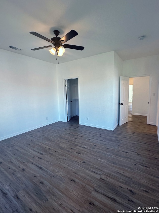 interior space with dark wood-type flooring, ceiling fan, and a walk in closet