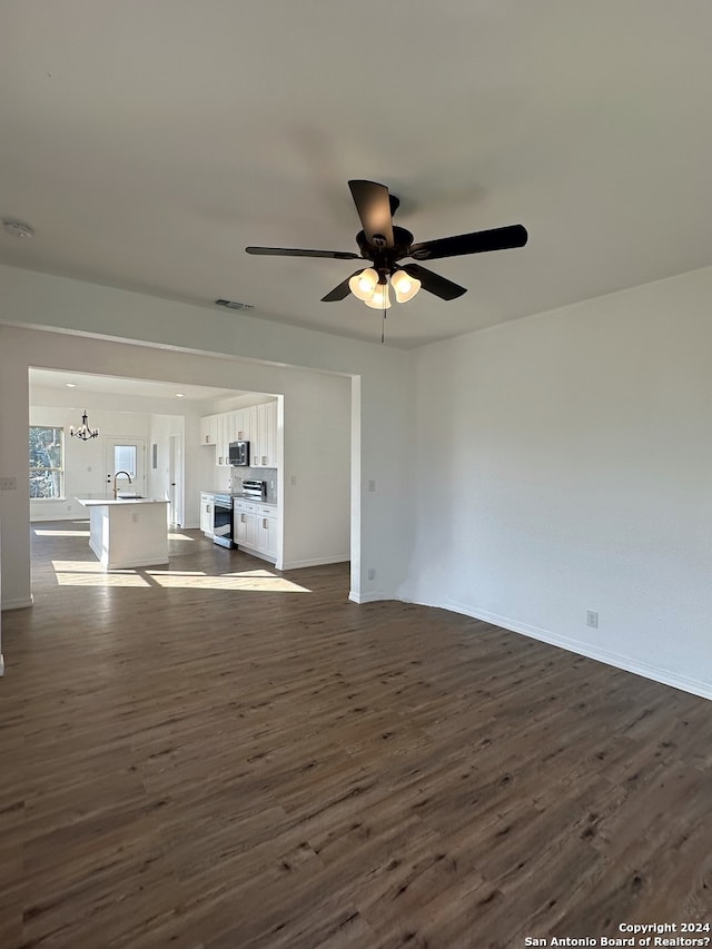 unfurnished living room featuring ceiling fan with notable chandelier, dark hardwood / wood-style flooring, and sink