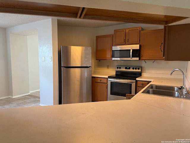 kitchen with stainless steel appliances, a textured ceiling, light tile patterned flooring, and sink