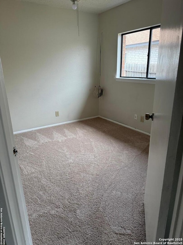 carpeted empty room featuring a textured ceiling and baseboards