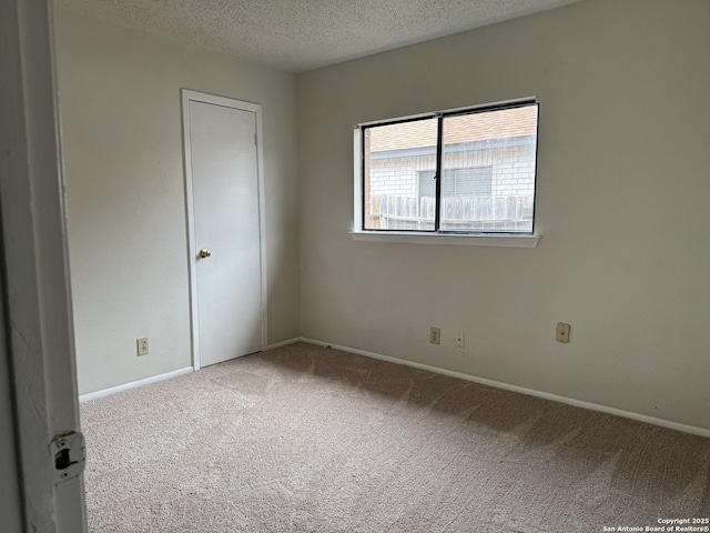 carpeted empty room with a textured ceiling and baseboards