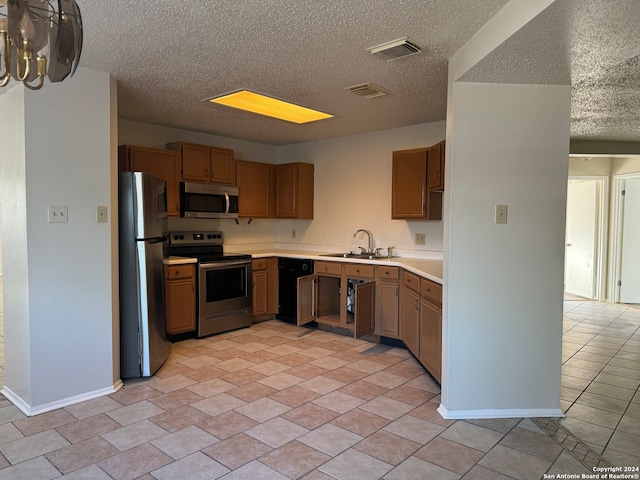 kitchen featuring a textured ceiling, stainless steel appliances, sink, and light tile patterned floors