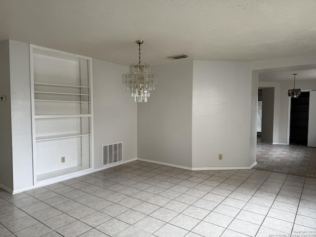 unfurnished dining area featuring built in shelves, a textured ceiling, visible vents, and a notable chandelier