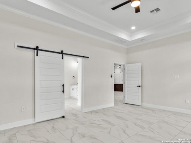 empty room with crown molding, a barn door, ceiling fan, and a raised ceiling