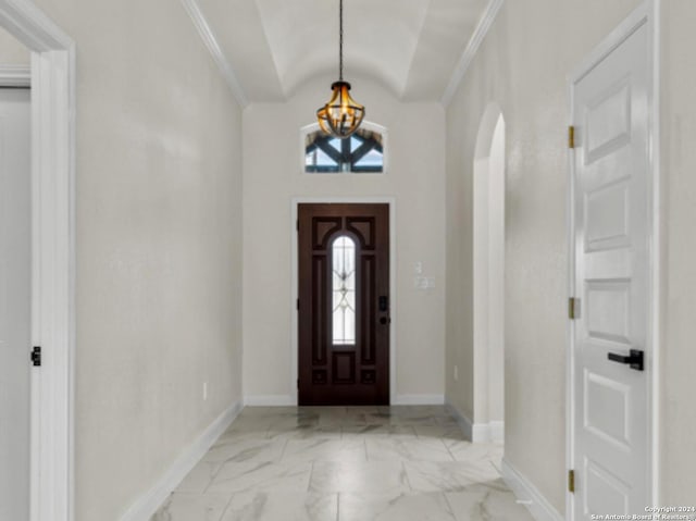 entryway featuring ornamental molding, vaulted ceiling, and a notable chandelier