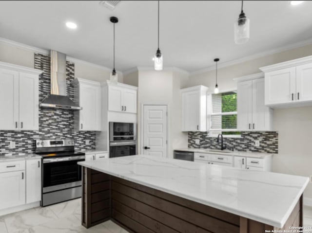 kitchen with a center island, appliances with stainless steel finishes, wall chimney range hood, and white cabinetry