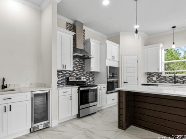 kitchen featuring decorative light fixtures, stainless steel appliances, white cabinetry, wall chimney exhaust hood, and beverage cooler