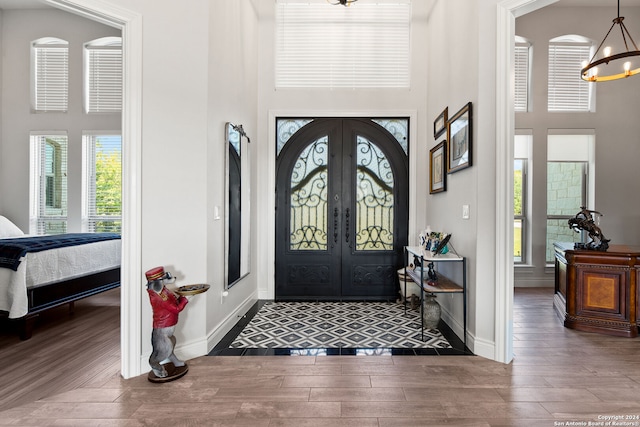 foyer entrance featuring a towering ceiling, wood-type flooring, and an inviting chandelier