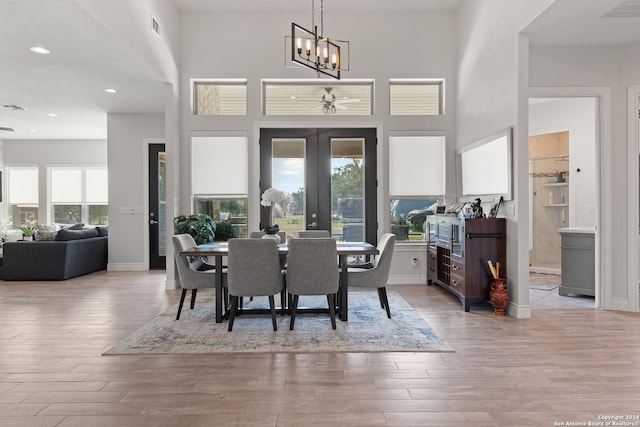 dining room featuring a high ceiling, french doors, a chandelier, and light hardwood / wood-style flooring